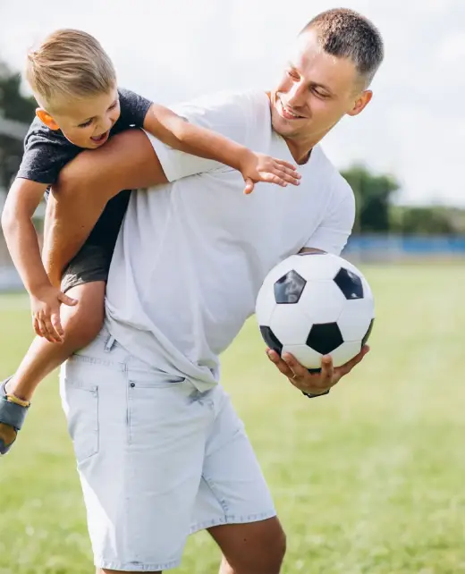 Otec s malým synom na rukách a futbalovou loptou